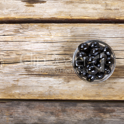 Black olives on a wooden background. View from above