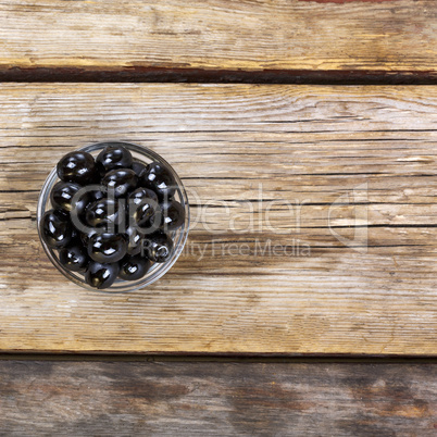 Black olives on a wooden background. View from above