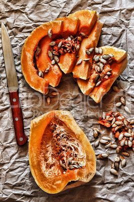 Pieces of ripe pumpkin and seeds on a background of crumpled packing paper.