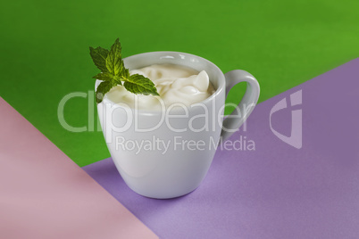 Minimal creative concept. Milk dessert in a white cup, decorated with mint on a green