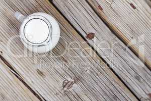 Natural food. A jug of cow milk on a wooden table, top view, closeup. Rustic style.