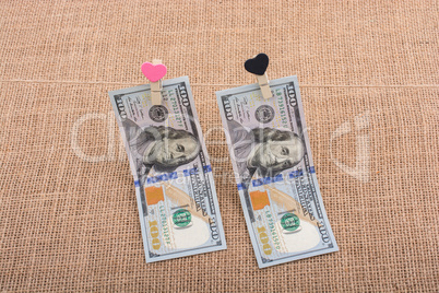 Dollar banknotes with a heart clip on a string