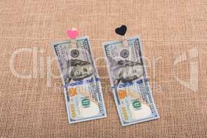 Dollar banknotes with a heart clip on a string
