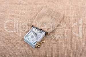 Retro key and bundle of US dollar in a sack