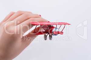 Hand holding a toy plane on a white background