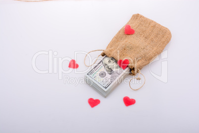 Red hearts and bundle of US dollarin a sack