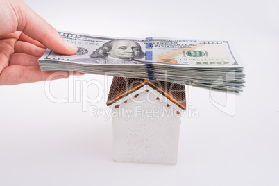 Hand holding American dollar banknotes on the roof of a model ho