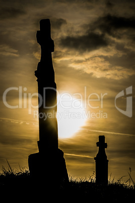 Graveyard at sunset dark clouds golden light.