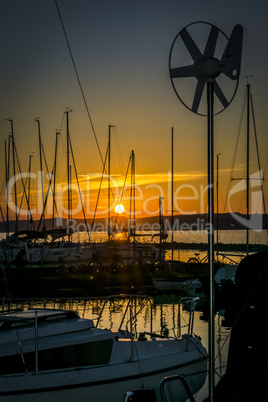 Silhouette of sailing boats on a calm lake at sunset.