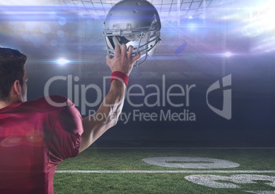 american football  player standing in stadium holding up helmet