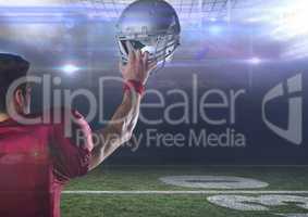 american football  player standing in stadium holding up helmet