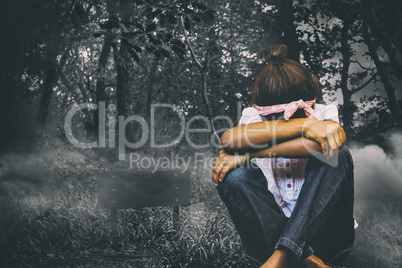 Composite image of tensed girl sitting against brick wall in school corridor