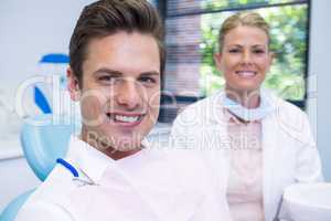 Smiling man and dentist sitting at dental clinic
