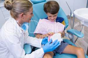 Dentist teaching boy brushing teeth on dentures
