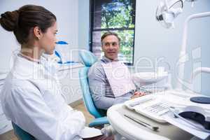 Man taking with doctor while sitting on chair