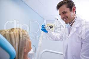 Dentist adjusting lamp while looking at patient in medical clinic
