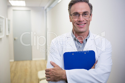 Dentist holding file while standing at lobby in dental clinic
