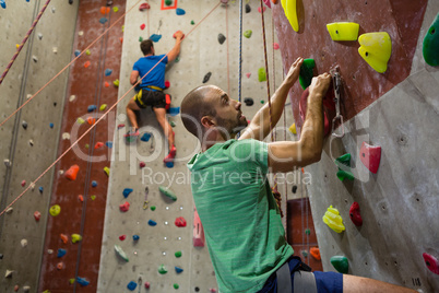 Fit athletes climbing wall in club