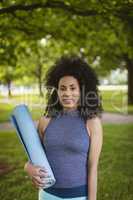 Woman holding exercise mat in the park
