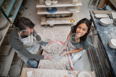 Overhead of male potter assisting female potter