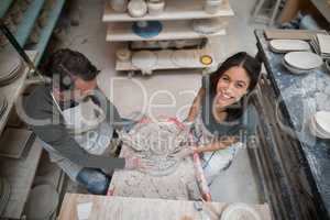 Overhead of male potter assisting female potter