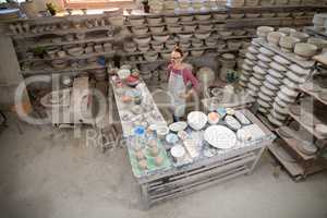 Overhead of female potter standing near worktop