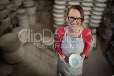 Overhead of female potter painting bowl