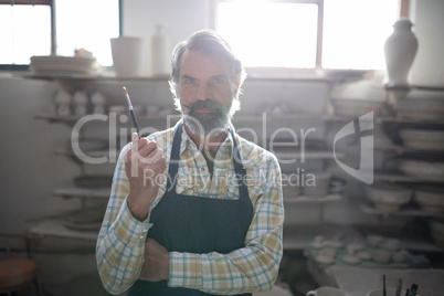 Portrait of male potter holding paint brush