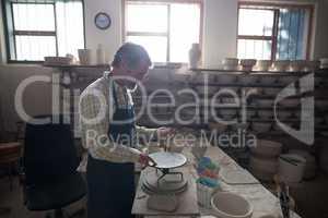 Male potter molding a clay on pottery wheel