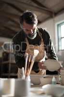 Male potter checking bowls at worktop