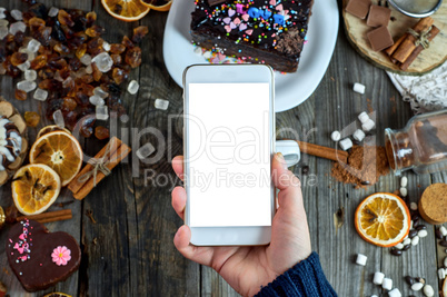 Female hand holding a smart phone on the table, white blank scre