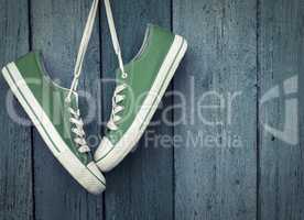 Green youth sneakers hanging on a nail