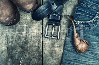 Detail of worn blue jeans and brown shoes on a wooden background