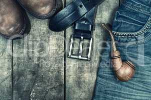 Detail of worn blue jeans and brown shoes on a wooden background