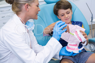 Dentist looking at boy brushing dentures