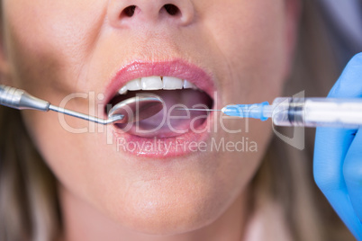 High angle view of dentist holding syringe by patient mouth