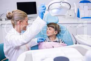 Side view of dentist adjusting electric light while boy sitting on chair