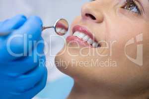 Dentist holding angled mirror by smiling woman at clinic