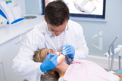 High angle view of dentist examining woman with dental equipments