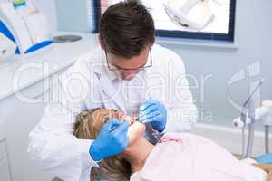 High angle view of dentist examining woman with dental equipments