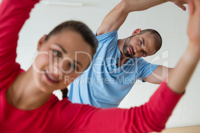 Portrait of male instructor exercising with student in health club