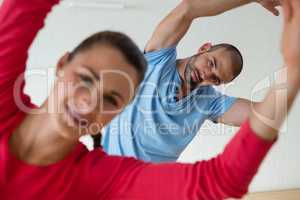 Portrait of male instructor exercising with student in health club