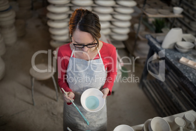 Female potter painting bowl