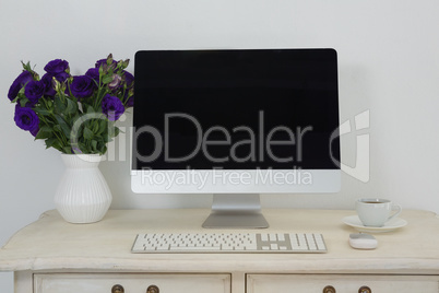 Desktop pc, vase and coffee on table