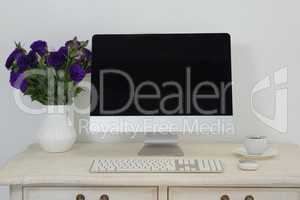 Desktop pc, vase and coffee on table