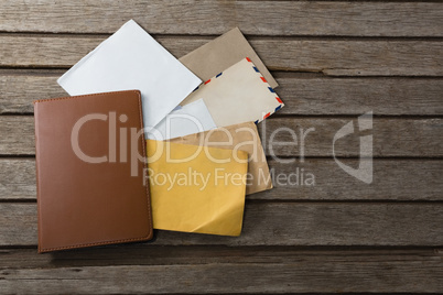 Various envelopes and diary on wooden plank