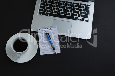 Black coffee, pen, notepad and laptop on black background