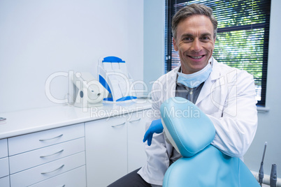 Portrait of smiling dentist standing by chair Portrait of smiling dentist standing by chair