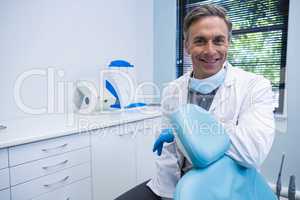 Portrait of smiling dentist standing by chair