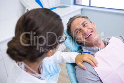 Patient sitting on chair while looking at dentist in medical clinic
